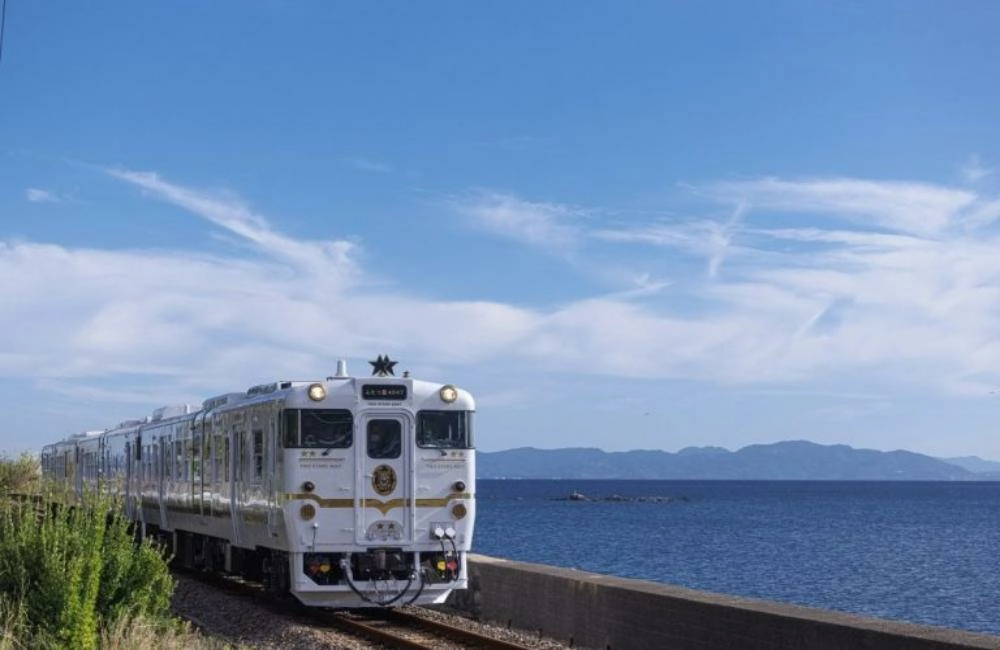 雙星4047觀光列車外觀，深藍車身搭配金色線條行駛於海岸線上